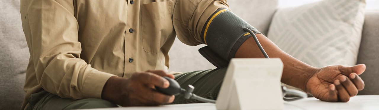 A man with a cuff on his arm, checking his blood pressure at home.