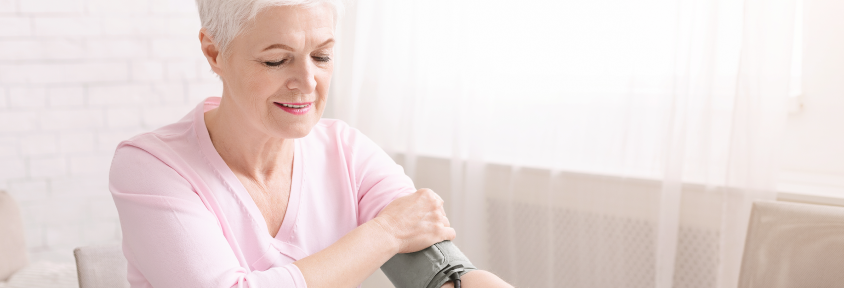 A senior, female breast cancer survivor takes her own blood pressure.