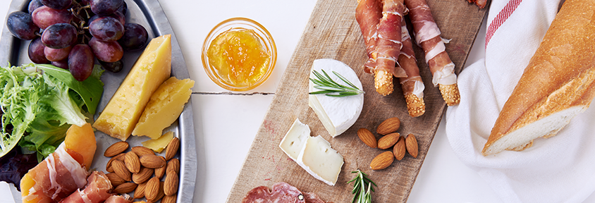 A healthy charcuterie board with various cheeses, vegetables, fruits, and herbs.