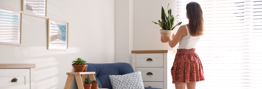 Young female decorating a sitting area in her bedroom with a plant and natural textures.