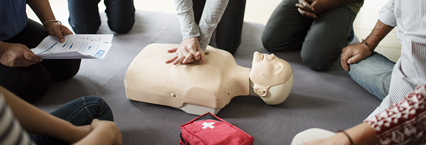 A young woman gives a CPR manikin chest compressions to prepare for a sudden cardiac arrest situation