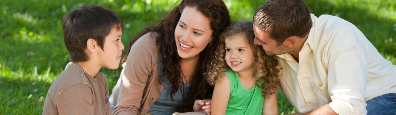 A family of four enjoying a summer picnic outside.