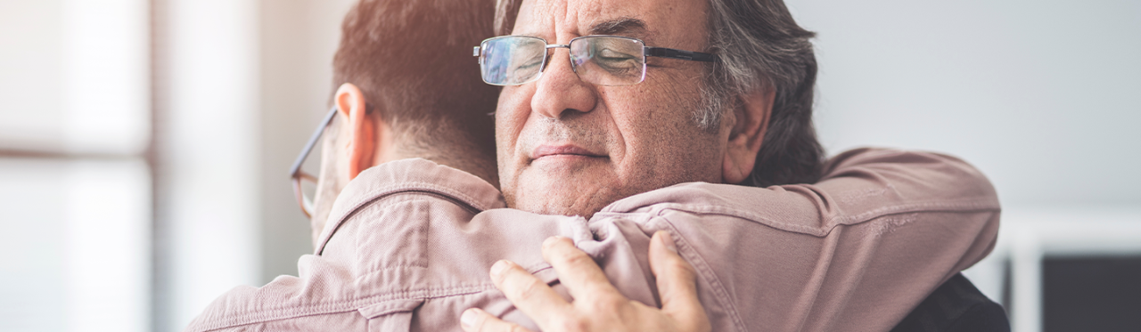 Father and his adult son hugging after talking about symptoms of depression.