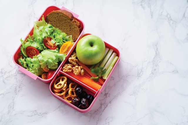 A pink bento box filled with healthy foods for a school lunch.