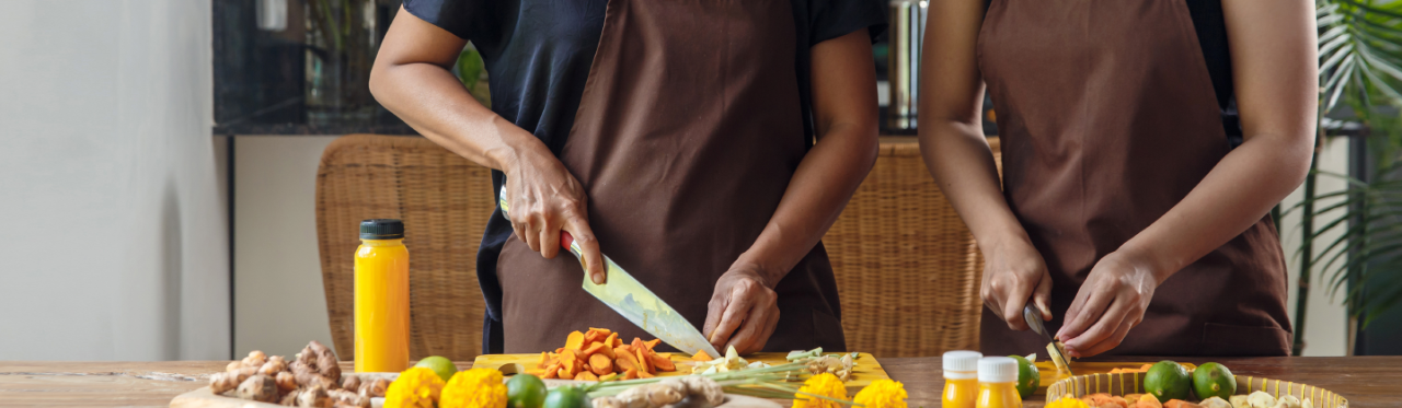 Two women in a kitchen cooking with medicinal ingredients from around the world.