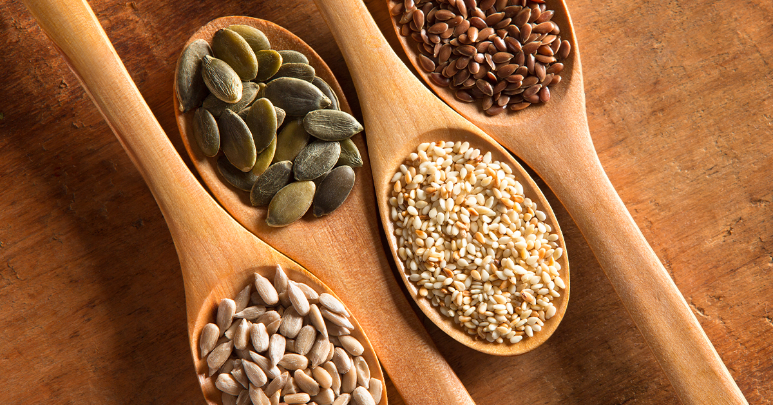 In preparation for seed cycling, spoons hold flax, pumpkin, sunflower, and sesame seeds.