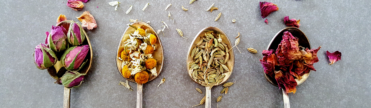 A number of wooden spoons with various edible flowers in them