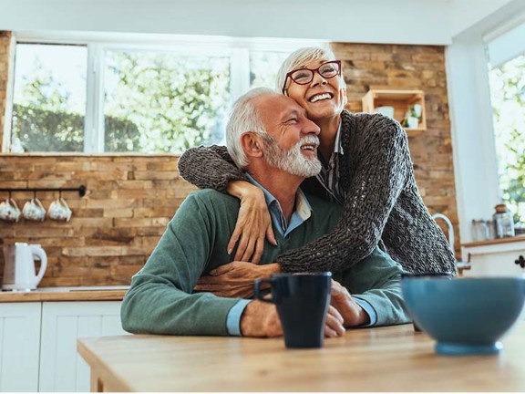 elderly couple hugging each other happily