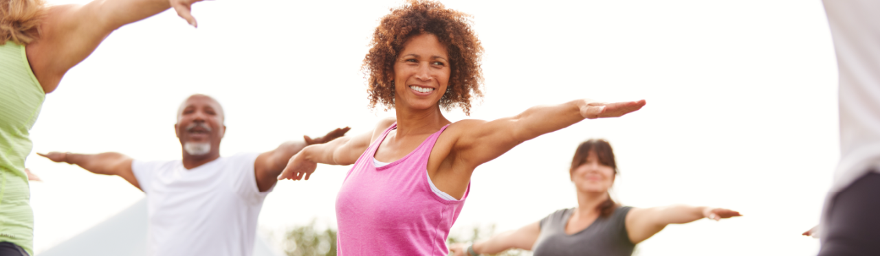 A group of adults practices yoga outside to relieve their stress.