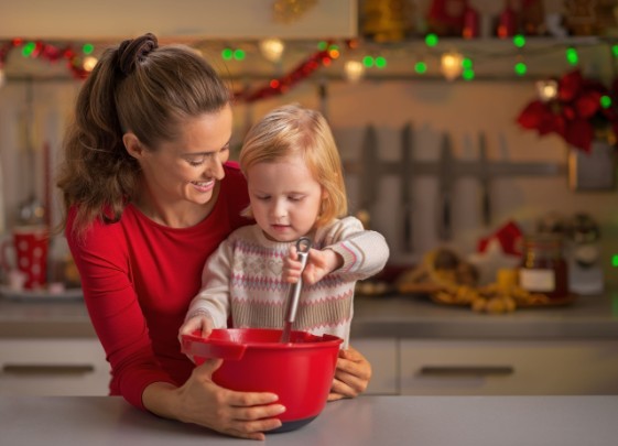 A mom and her daughter stir something in a bowl in the kitchen