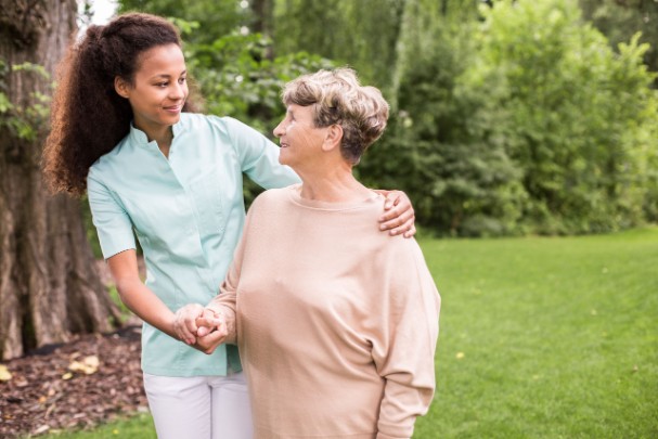 A young woman embraces an elderly woman outdoors