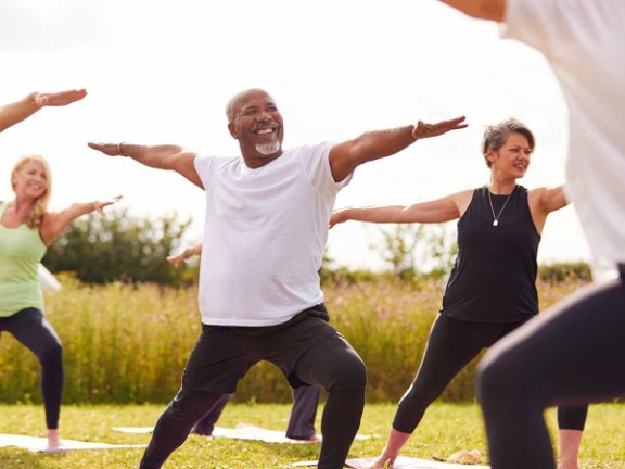 Older-aged adults doing yoga outdoors