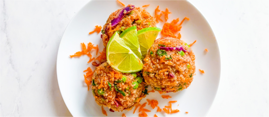 Colorful Thai quinoa salad is on a plate with slices of lime and shredded carrots.