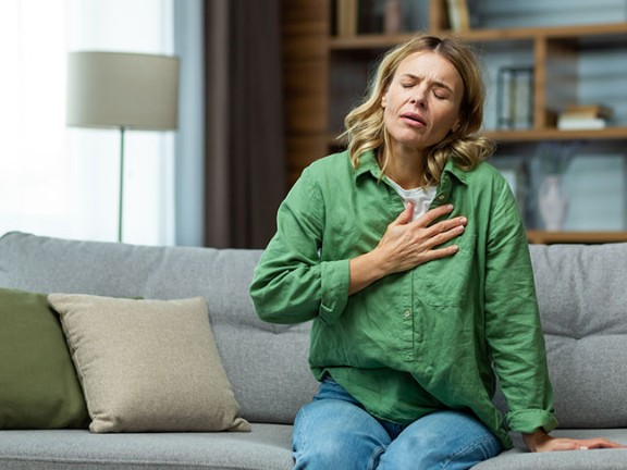Woman placing hand over chest in discomfort 