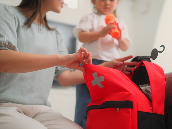 A mother preparing a hurricane kit while watching her child. 