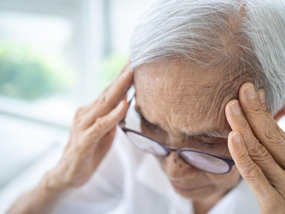 An elderly lady pressing against the temple of her head. 