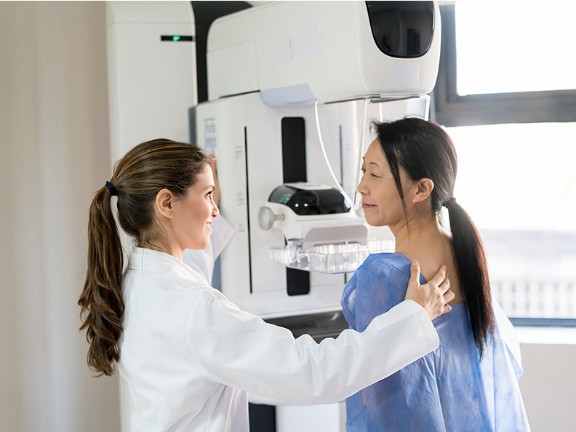 Physician conducting a x-ray mammogram screening with a patient.