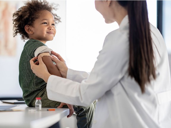 A child with their sleve rolled up ready for their vaccine. 