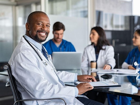African American physician smiling at camera during a team meeting. 