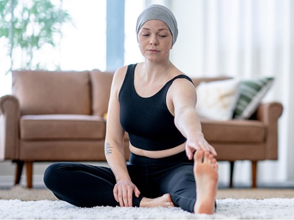 Cancer patient stretching at home on carpet