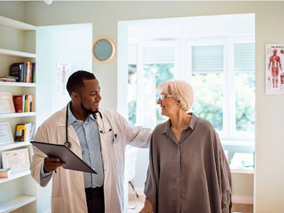 An elderly person smiling at their physician during a doctor visit