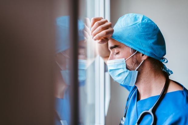 An exhausted physician leaning against the wall