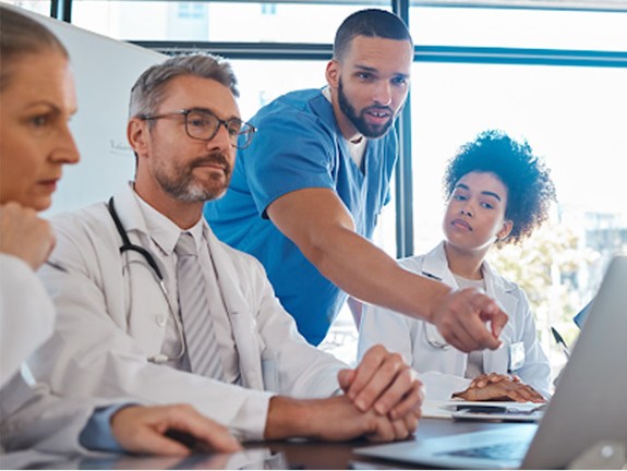 Group of medical providers looking at a screen in a conference room