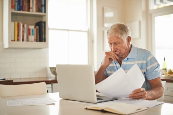 Elderly gentlemen reviewing documents while on laptop