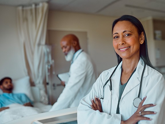 A physician smiling while the other physician is checking in a patient