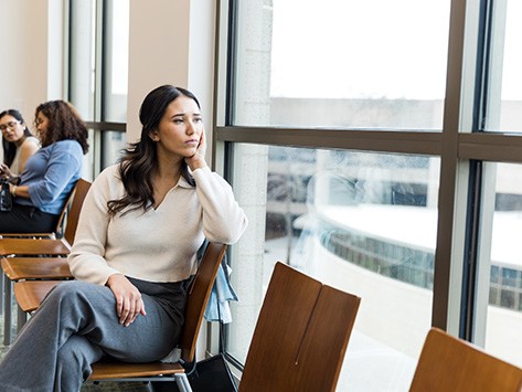 A person looking outside of an office building window in doubt 