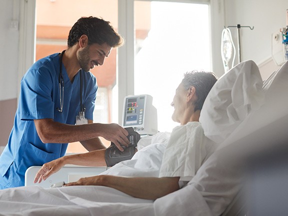 Patient smiling at doctor while laying on a hospital bed.