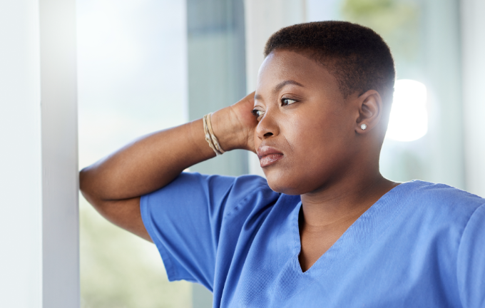 an exhausted health care worker looking outside a window 