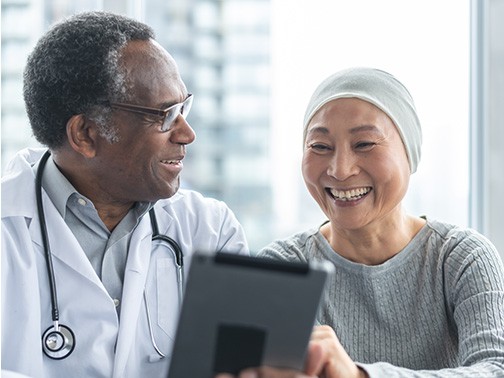 A doctor and patient smiling while reviewing results on a tablet