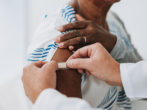 Physician placing bandage over patient's right arm.