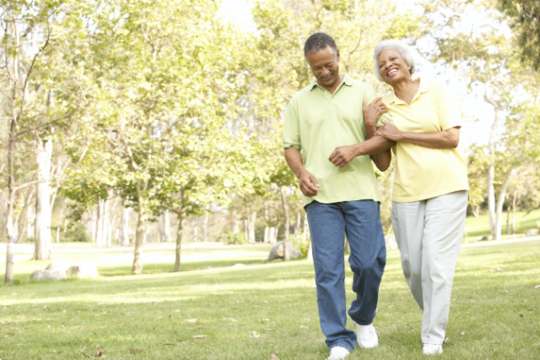 An elderly couple take a leisurely stroll through a park 