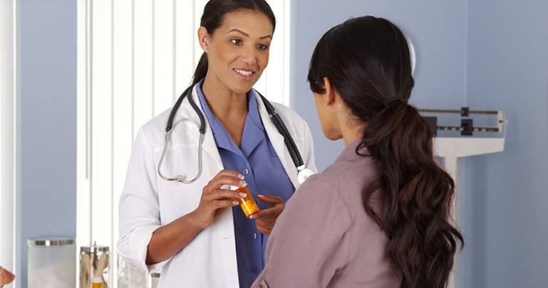 Doctor holding prescription bottle, talking to patient