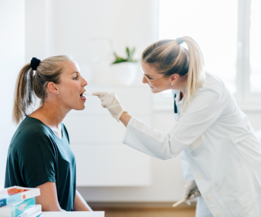 An ear, nose, and throat specialist examines a female patient during a regular visit. 