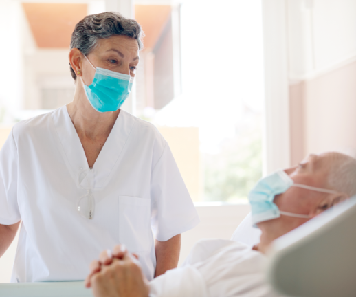 An emergency care doctor talks with a man as he lays in a bed in the emergency room.