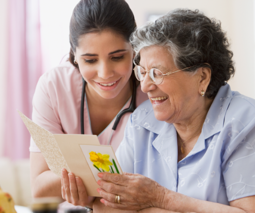 A geriatric nurse reads a card from her senior patient's family. 