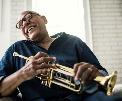 A senior man laughs while taking a break from playing the trumpet with his band.