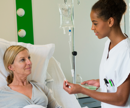 A nurse provides medication to a woman while she receives her infusion. 