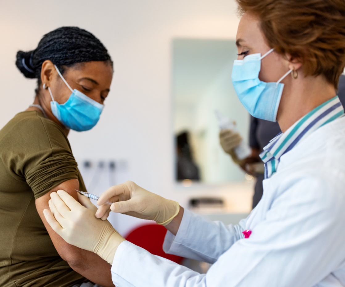 A pathologist gives a vaccine to a woman during her doctor's appointment.