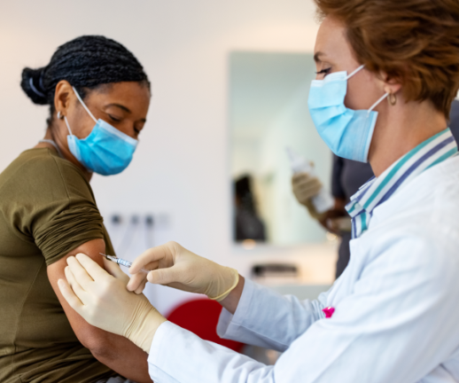 A pathologist gives a vaccine to a woman during her doctor's appointment.