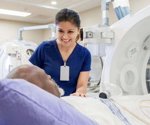 A female radiology assistant comforts a male patient before performing a scan.