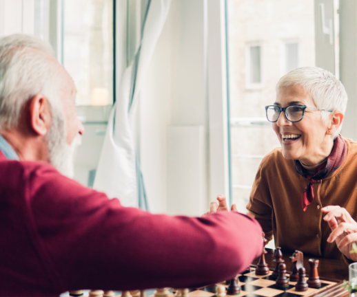A woman laughs with her spouse over a game of chess after recovering from neurosurgery.