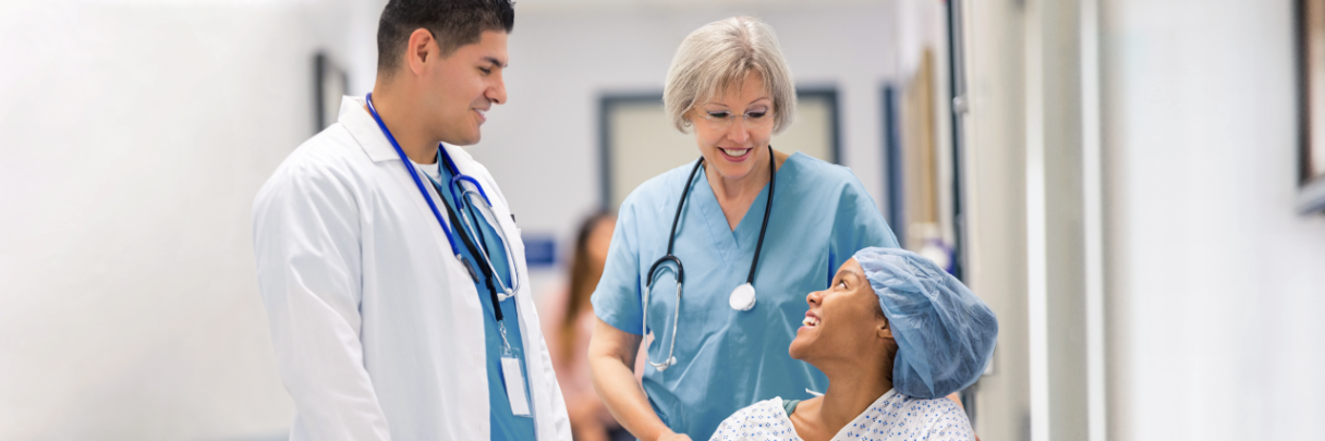 A doctor and a nurse speak with a patient about her procedure before leading her to surgery.