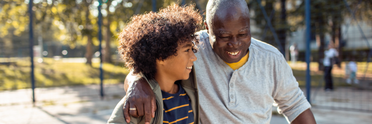 A senior man and his grandchild finish playing basketball at the playground.