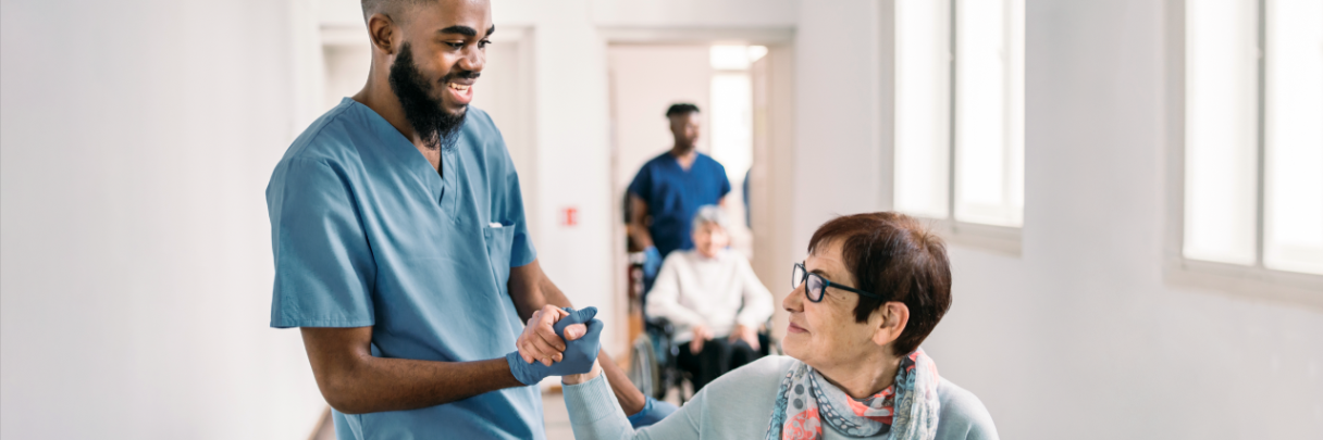 A nurse holds hands with a woman in a wheelchair as she prepares for a rheumatologist appointment.