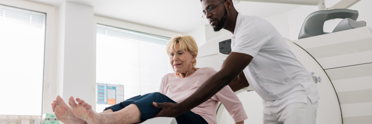 A male nurse helps a patient get into the proper position for her MRI scan.