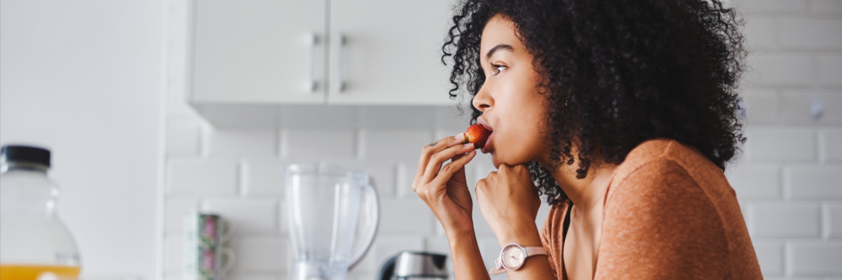 A young woman snacks on a plate of assorted fruits to help improve her digestive health.